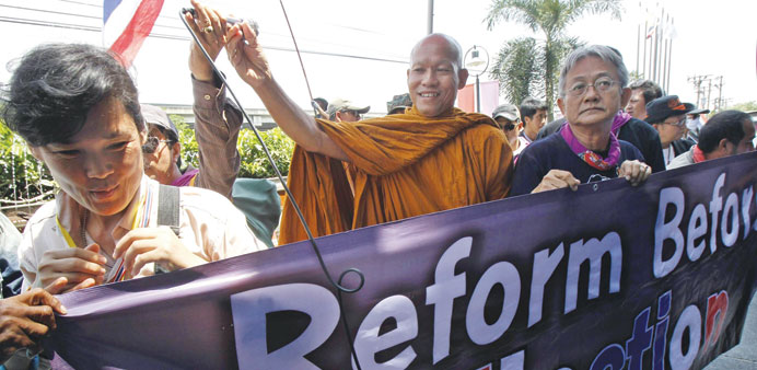 Thai Buddhist monk and protest leader Luang Pu Buddha Issara gestures as his supporters hold a banner during a rally outside a hotel in Bangkok yester