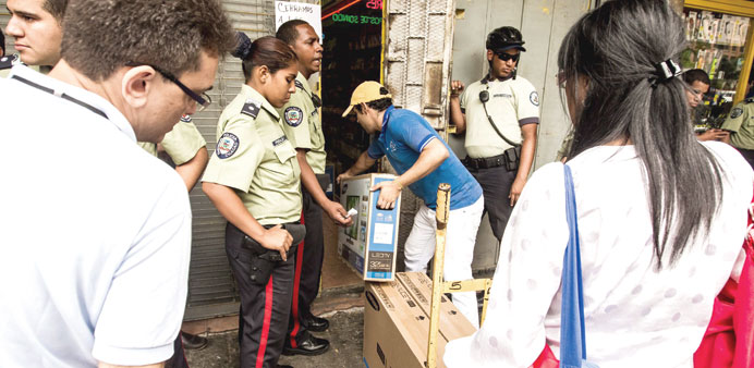 People buy appliances from a store in Caracas under the watchful eye of the police. The store cut the prices of its goods to avoid being shut down or 