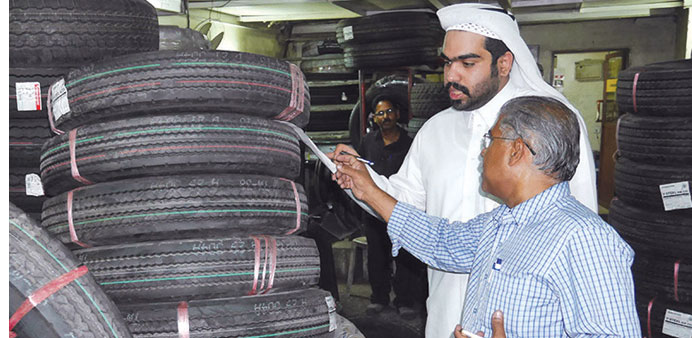  An inspector from the Ministry of Economy and Commerce examines tyres at a shop on Salwa Road.