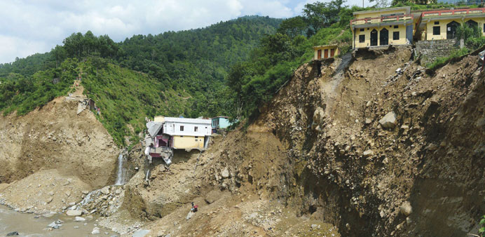 A damaged house is perched on the mountainside at Silli, in the flood-affected area of northern Uttarakhand state yesterday.