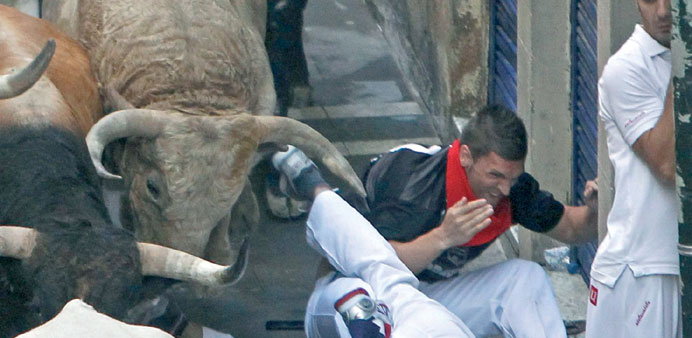 Runners or u2018mozosu2019 stumble as they are chased by bulls from Torrestrella ranch, during the fifth bull run of the San Fermin festival.