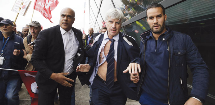 Police officers help Air France director Pierre Plissonnier, nearly shirtless, escape demonstrators in Roissy-en-France.