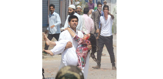 A Kashmiri man carries an injured woman during a clash between protesters and police in Srinagar yesterday.