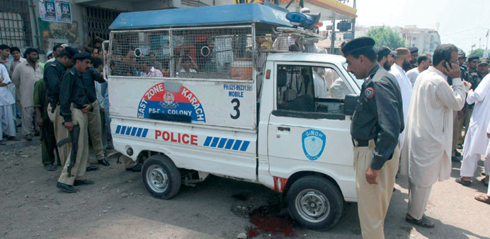 Police inspect the scene after gunmen attacked a police vehicle in restive Karachi yesterday.
