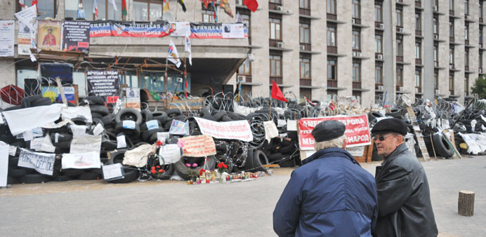 Residents sit on a bench near a barricade outside the regional state building in Donetsk.
