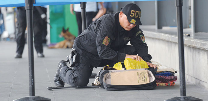 A police bomb disposal unit member inspects an abandoned bag in the departure area of terminal three of the airport in Manila yesterday, hours after a