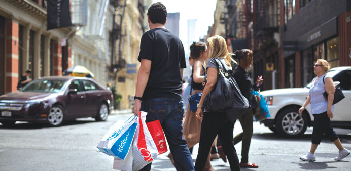 Shoppers carry their purchases while crossing the street in New York.  Strong household spending and robust exports kept the US economy on solid groun