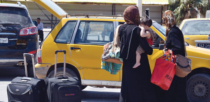 Libyan women, fleeing violence in their country, wait next to their luggage after entering Tunisia through the southern border crossing at Ras Jedir y