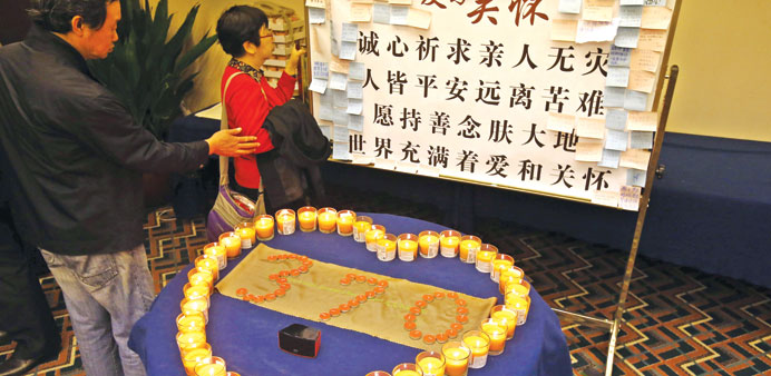 Relatives of passengers on the missing aircraft read dedication messages beside lit candles in a heart-shaped arrangement at a hotel in Beijing.
