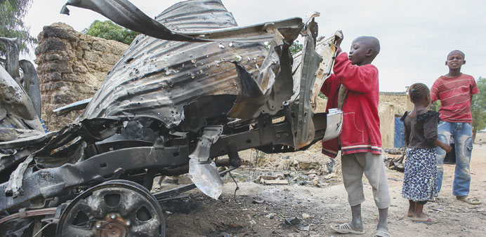 Children from Mali look at debris of destroyed vehicles used by militants after it was hit in French airstrikes in the recently liberated town of Diab