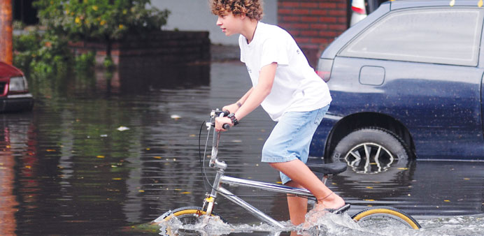 A boy rides a bicycle through a flooded street in La Plata yesterday.