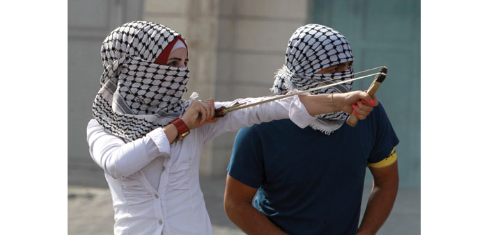 A young Palestinian woman uses a slingshot during clashes with Israeli security forces yesterday in Bethlehem.