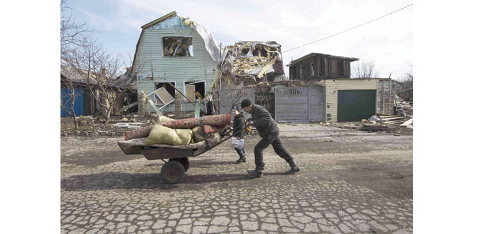 A man pushes a wheelbarrow past a house damaged by fighting in the town of Debaltseve.