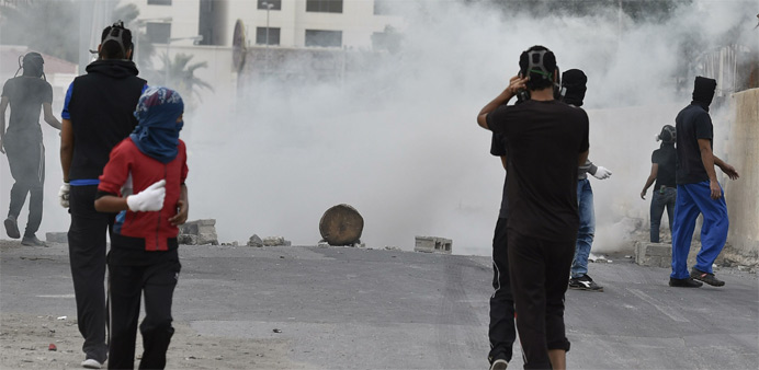 Protesters take cover from tear gas fired by riot police during clashes