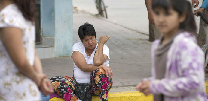 A woman sits on the sidewalk after a tremor in El Galpon, northwest Argentina.