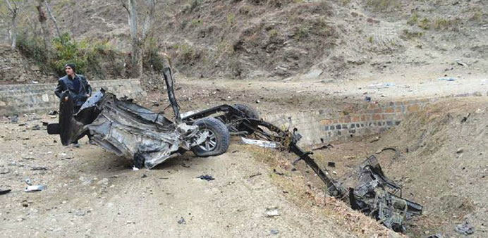 A Pakistani policeman stands beside the wreckage of a destroyed police vehicle after a roadside bomb explosion in the Martoong area of Swat valley yes