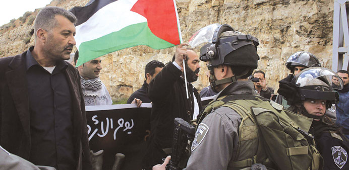 A protester holds a Palestinian flag in front of Israeli border police during a demonstration marking Land Day near the West Bank town of Bethlehem ye