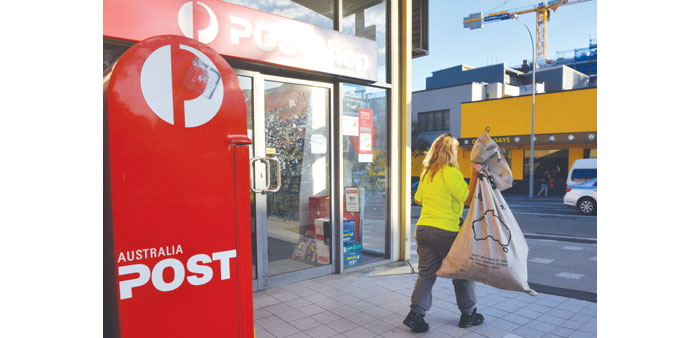 A worker carries a sack of letters after emptying a post box outside an Australia Post office in Sydney.
