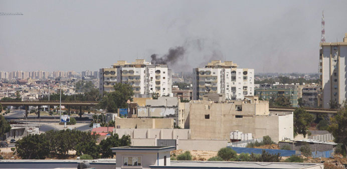 Smoke rises near buildings during heavy fighting between rival militias near the airport in Tripoli yesterday.