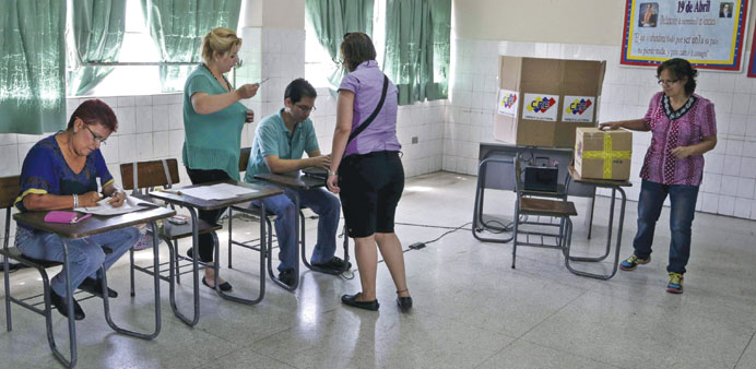 A woman casts her marked ballot in a box during opposition coalition primaries for parliamentary election in Caracas yesterday.