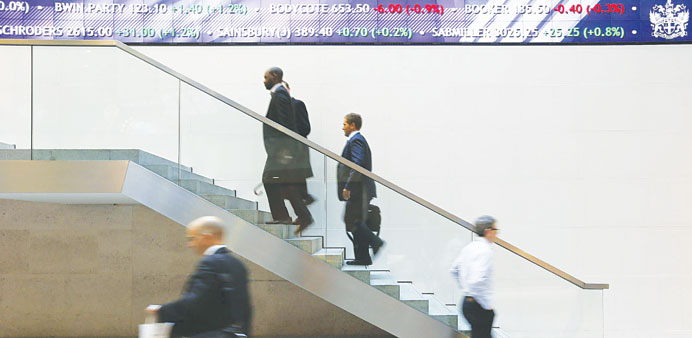 People walk past an electronic information board at the London Stock Exchange in the City of London. The benchmark FTSE 100 index yesterday added 0.71