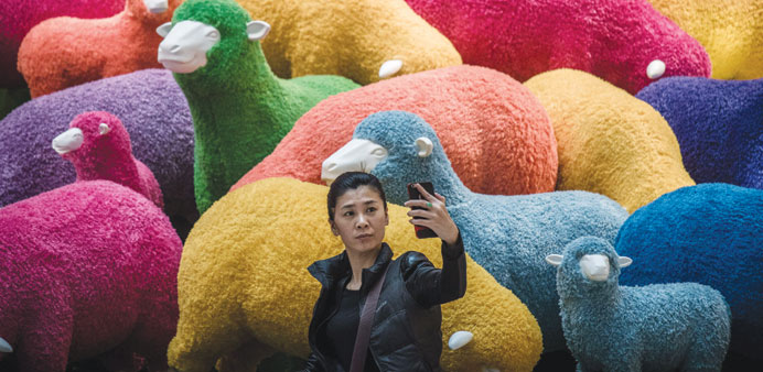 A woman takes a selfie yesterday in front of a multi-coloured sheep installation displayed in a shopping mall for the Chinese New Year celebrations in