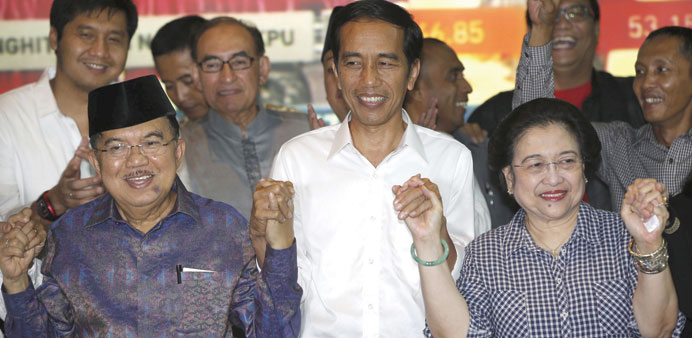 Indonesian presidential candidate Joko u201cJokowiu201d Widodo (centre) and his running mate Jusuf Kalla (left) celebrate with their party chairwoman Megawati