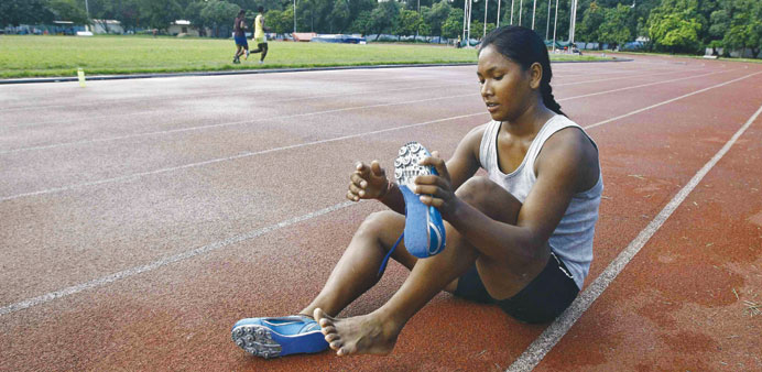Indian heptathlete Swapna Barman removes her shoes after a practice session at Salt Lake stadium in Kolkata.