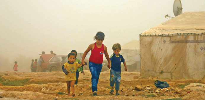 Syrian children walk amid the dust during a sandstorm yesterday at a refugee camp on the outskirts of the eastern Lebanese city of Baalbek. 