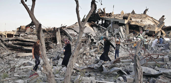 Palestinians walk in the rubble of destroyed houses in Gaza Cityu2019s Shejaiya neighbourhood yesterday. 