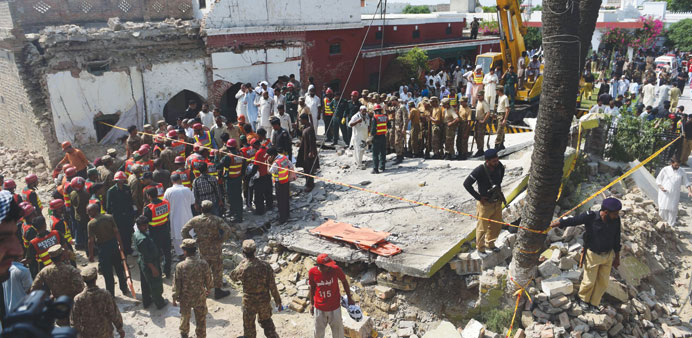 Pakistani army and rescue officials gather around a collapsed building at a suicide bomb blast site in the village of Shadi Khan some 70km north-west 