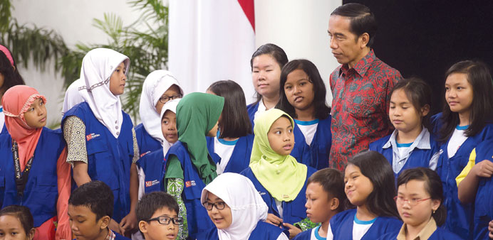 Indonesia President Joko Widodo talks to elementary school students, playing the role of young reporters, at the Presidential Palace in Jakarta yester