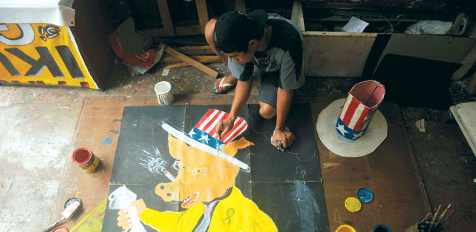 An activist applies finishing touches on a protest banner in Manila yesterday.