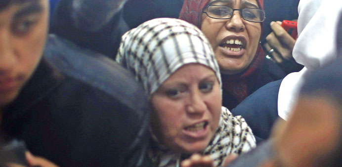 Two women hoping to cross into Egypt shout toward border officials as they wait with other Palestinians to register their names at the Rafah crossing 