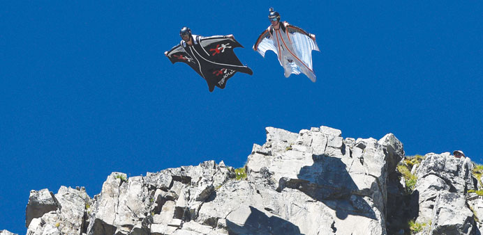 Two men jumping from the top of the Brevent mountain to fly in wingsuit over the French ski resort of Chamonix. 