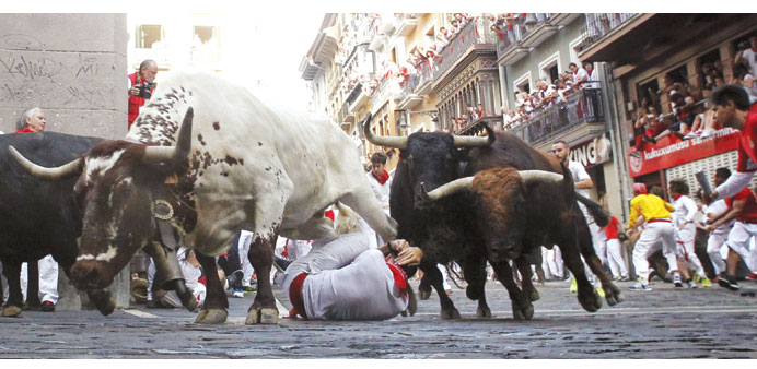 A steer jumps over a fallen runner as two Jandilla fighting bulls follow behind at the Mercaderes curve during the first running of the bulls of the S