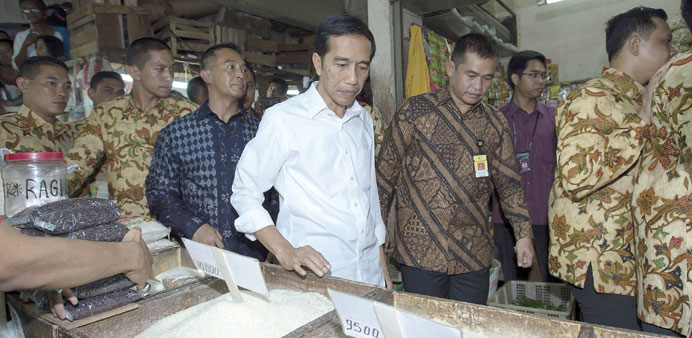 Indonesian President Joko Widodo walks past a rice vendor during a visit to a market in Jakarta yesterday.