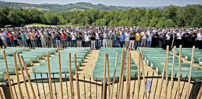 Bosnian Muslims pray in front of the coffins of their relatives during a mass funeral yesterday in the village of Biscani, near Prijedor.