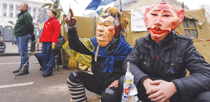 Protesters wearing masks depicting Ukrainian President Viktor Yanukovych and Russian President Vladimir Putin attend a rally at Independence Square in