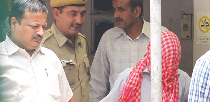   Policemen in plain clothes escort the juvenile accused (with face covered) in the New Delhi gang-rape case, after the court hearing at the Juvenile 
