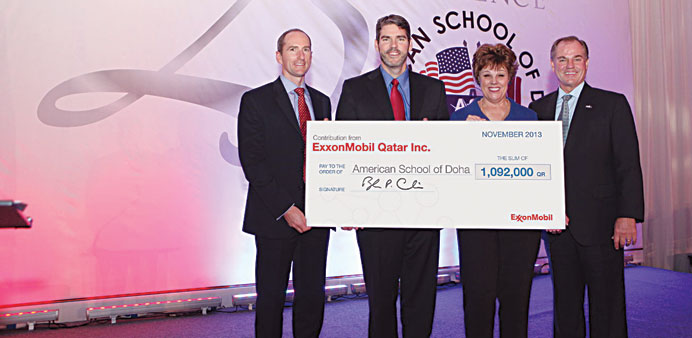 ExxonMobil Qatar and American School of Doha officials posing with a cheque.