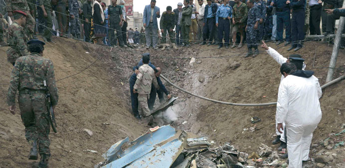 Air force officers and police recover wreckage at the site of the jet crash in Sanaa yesterday.