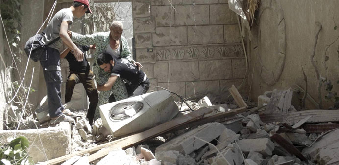 Residents help an injured man at a site damaged by what activists said was shelling by pro-regime forces in the Damascus suburb of Saqba yesterday.