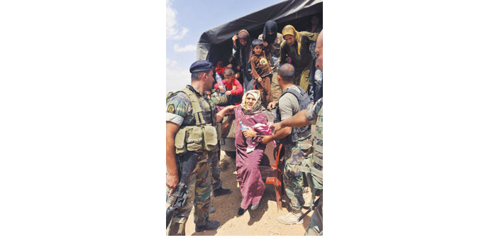 Lebanese soldiers help Syrian refugees, fleeing the violence in Arsal, dismount a truck in Al Labwa in eastern Bekaa Valley yesterday. 