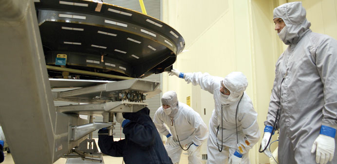Workers at Lockheed Martin Space Systems, south of Denver, manoeuvre an antenna that will be fitted onto MAVEN, a Mars orbiter.