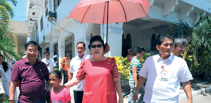 Philippine former first lady Imelda Marcos (centre) walking with a girl as she arrives for a campaign trail in Banna town, Ilocos Norte province, nort