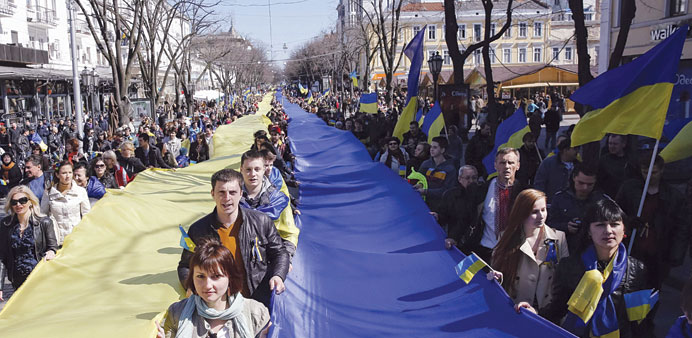 People hold long lengths of cloth in the colours of the Ukrainian national flag at a rally in Odessa against the annexation of the Black Sea peninsula