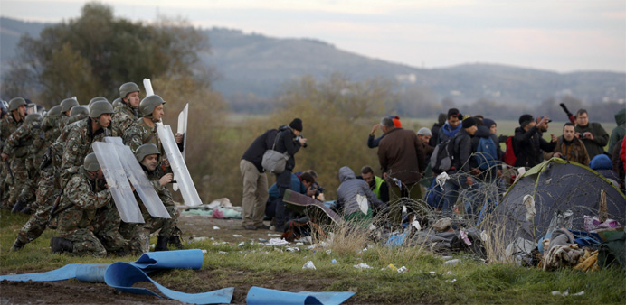 Macedonian police officers take positions after migrants tried to cross the border from Greece into Macedonia