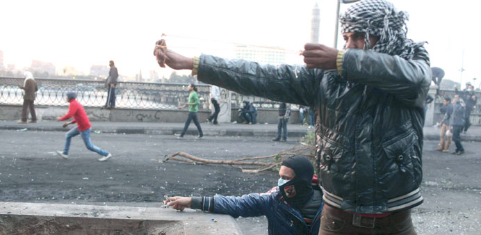  Protesters use slingshots to launch stones at riot police during clashes in Cairo yesterday.