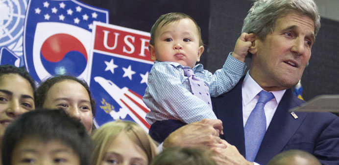 US Secretary of State John Kerry carries 8-month-old Andrew Belz as he poses for photos with the children of US troops and US embassy personnel at Col